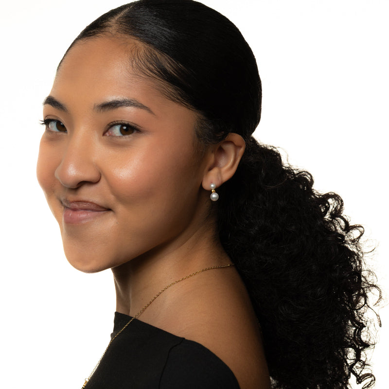 Woman with a ponytail wearing Luna Double Pearl Studs, shot on a white background