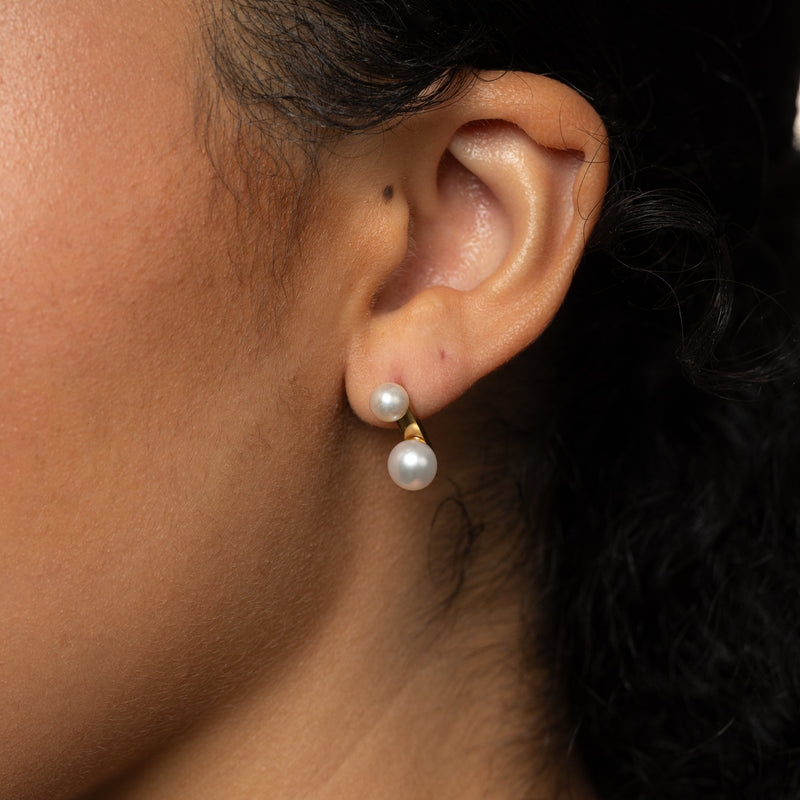 Close-up of an ear wearing gold Luna Double Pearl Studs