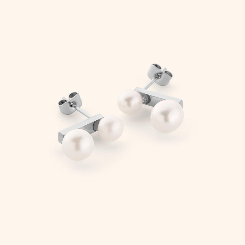Luna Double Pearl Studs — Silver stud earrings with two different sized pearls, shot on a light background