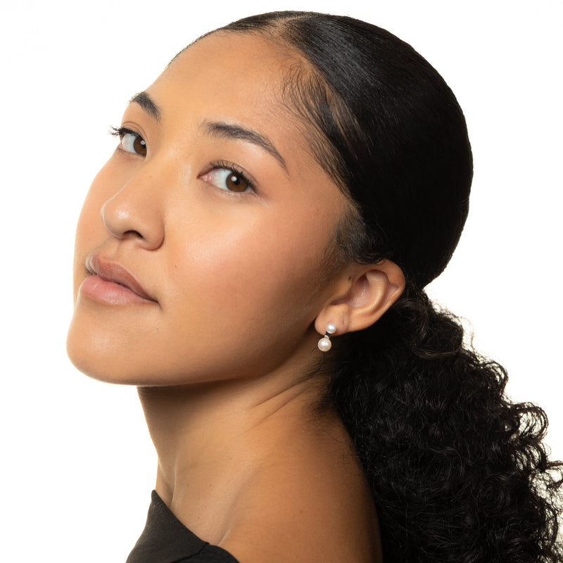 Woman with a ponytail wearing a gold Luna Double Pearl Studs, shot on a white background