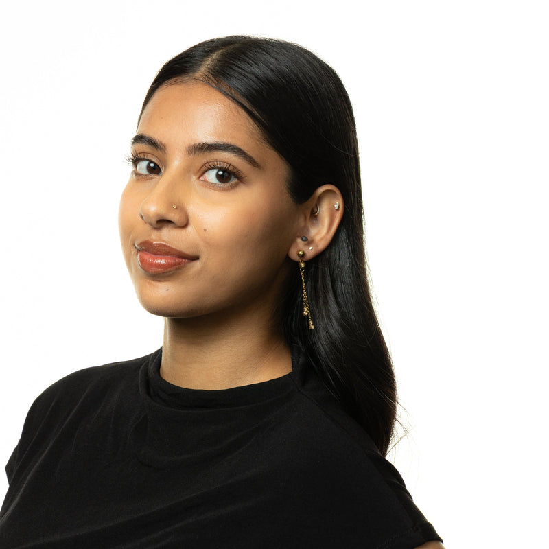 Woman wearing gold Noor Chain Drop Earrings styled with a black high-neck top