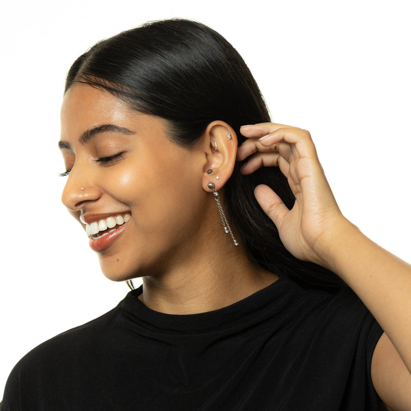 Woman wearing silver Noor Chain Drop Earrings with double chain drops, styled with a black top.