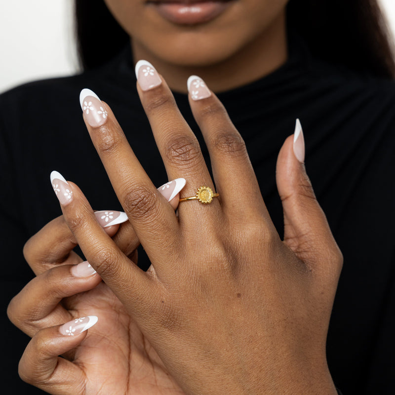 Close-up of hands , one hand showing the gold Solara Bloom Ring centered on the finger.